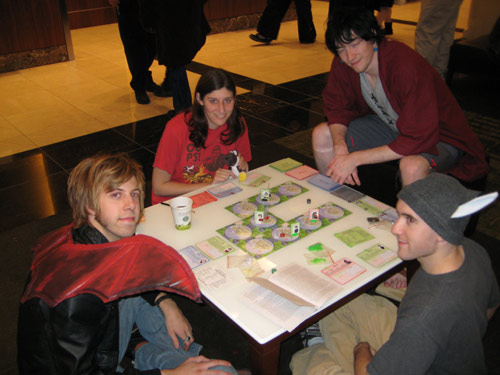 A group plays Collateral Damage: The Anime Board Game in the hotel lobby Saturday night